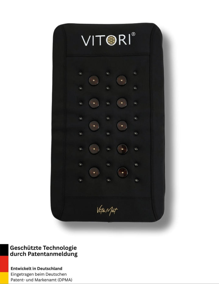 Die schwarze VITORI® VitaMat® Mini-Matte von VITORI verfügt über mehrere runde Massageknoten in einem Raster, mit deutschem Text, der die patentierte VitaWave®-Technologie und Entwicklung in Deutschland hervorhebt, und einem Branding für erweiterte Funktionalität an der Unterseite.