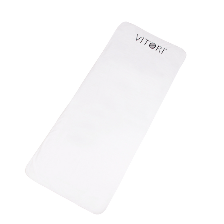 Ein rechteckiger weißer Bezug für Premium Kristallmatte von VITORI® mit abgerundeten Ecken und einer hygienischen Abdeckung zeigt an einem Ende den Markennamen in dunklen Buchstaben auf einem schlichten schwarzen Hintergrund.