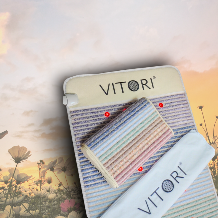 Das VITORI® Paket Ultimate-Set besteht aus einem pastellgestreiften Kristallmatte-Heizkissen, einem zylindrischen Ultimate-Kissen und einem weißen Gurt, wunderschön präsentiert vor der Kulisse eines Sonnenuntergangs mit Wildblumen.