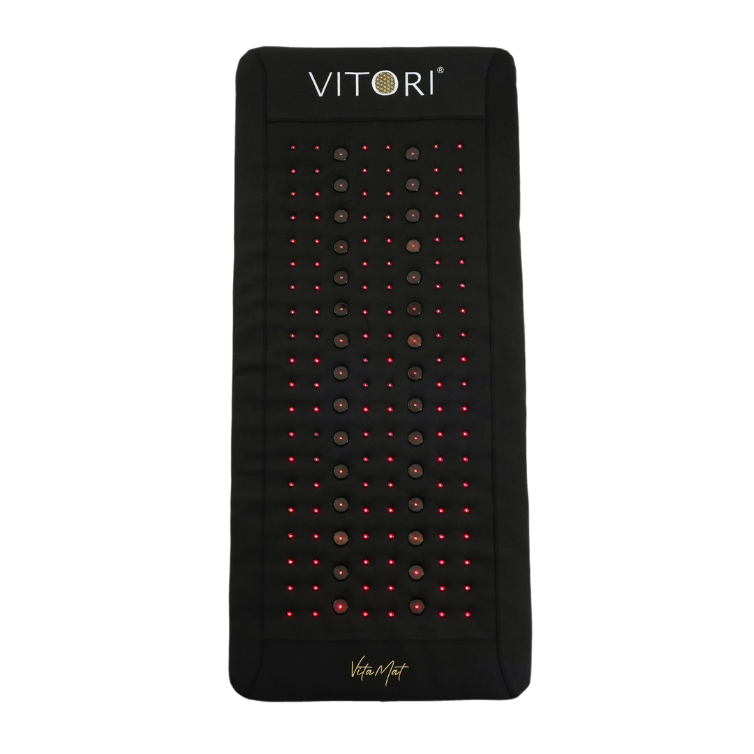 Die VITORI® VitaMat® ist eine schwarze rechteckige Matte mit Reihen leuchtend roter LEDs, zentralen runden Knoten, innovativer VitaWave® Technologie, dem VITORI-Logo oben und „VitaMat“ unten.