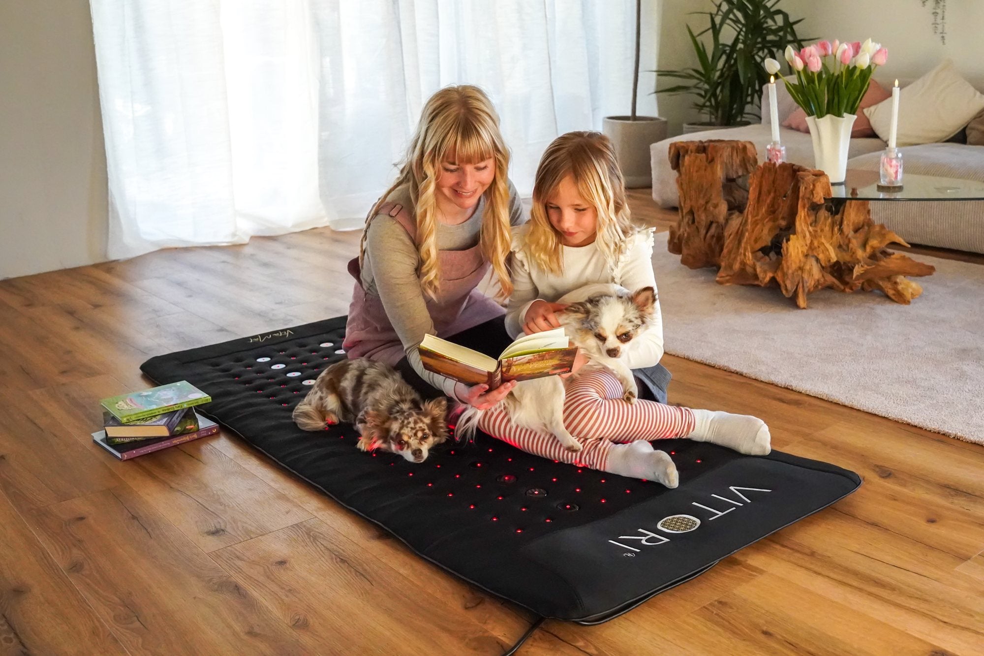 Mutter und Tochter lesen gemeinsam auf der VitaMat im Wohnzimmer
